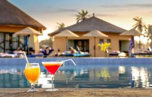 科洛里Bamboo Village Resort的坐在泳池旁的桌子上喝两杯饮料