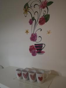 瓦拉日丁Sweet Dreams Apartment的摆在架子上的一排咖啡杯,带花瓶