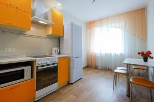 托木斯克OK! Советская 98 №1的厨房配有橙色橱柜和桌子