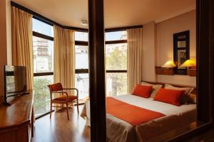 马德普拉塔卓越公寓酒店的一间卧室配有带橙色枕头的床和窗户。