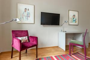 玛丽亚温泉Boutique Hotel SwissHouse的客厅配有粉红色的椅子和电视