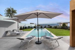 StérnaiAmaré Chania Luxury Residence的一个带遮阳伞和椅子的庭院和一个游泳池