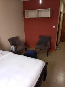 内罗毕Nairobi west suite的酒店客房,配有一张床和两把椅子