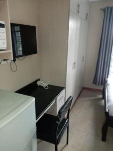 内罗毕Nairobi west suite的客房设有一张桌子、一把椅子和一台电视