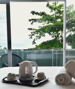 GodogNegla Beach Villa的茶壶和茶杯放在窗前的桌子上