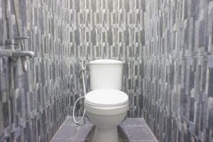 不拉士打宜OYO 1696 Sapo Rumbia的浴室设有白色卫生间,位于瓷砖墙壁上