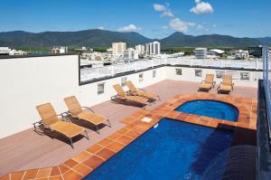 凯恩斯Cairns Central Plaza Apartment Hotel Official的一个带椅子的阳台和一个位于大楼内的游泳池