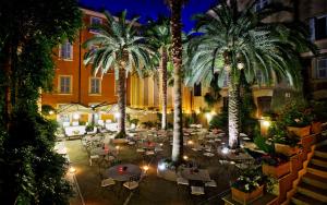 罗马旁特西斯托酒店的庭院设有桌子,晚上种植了棕榈树