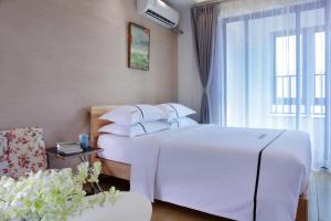 海口克拉尔绿邸酒店(免费24小时美兰机场/动车接送)的卧室设有一张白色大床和一扇窗户。