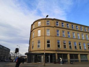爱丁堡Edinburgh Central Accommodation的一座棕色的建筑,前面有一位女人