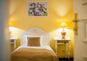 里加古腾堡酒店的一间卧室配有一张白色的床和两张带台灯的桌子。