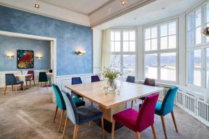 特里尔胡格尔别墅酒店的用餐室配有木桌和五颜六色的椅子