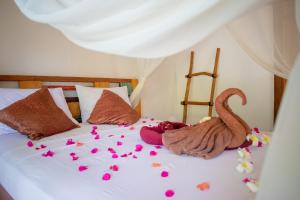 吉利特拉旺安Jati Village, Party Hostel and Bungalows的一张床上有粉红色花瓣的床
