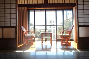 熊野市Yadokari Kumano的窗户前设有三把椅子和一张桌子的房间