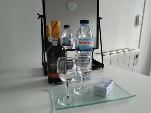 波尔图Guest House Triunfo的柜台上的一瓶水和两杯酒杯