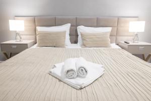 斯勒尼克Hotel Roberto Slanic Prahova的一张带两条毛巾和两盏灯的床