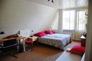 埃丹伊丹住宿加早餐酒店的一间卧室配有一张带粉色枕头的床和一张书桌