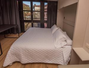 利亚内斯Apartamentos Puerta de Llanes的卧室配有白色的床和窗户。
