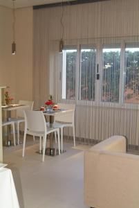 卡利亚里B&Beach Cagliari guest house的一间设有白色椅子和桌子的用餐室以及窗户。