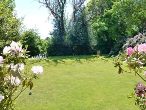 拉伊Flackley Ash Country House Hotel的种有树木和粉红色花卉的大型草地庭院