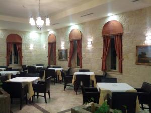 拉马拉Alhambra Palace Hotel Suites - Ramallah的一间带桌椅和红色窗帘的餐厅