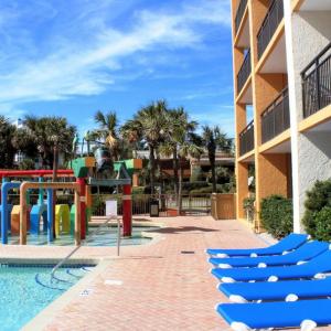 默特尔比奇Caravelle Resort by Palmetto Vacations的度假村的游乐场,设有蓝色椅子和游泳池