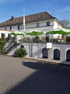 BetzdorfHotel Bürgergesellschaft的前面有桌子和绿色遮阳伞的建筑