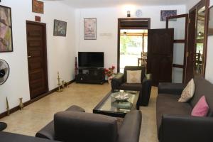 锡吉里亚Thal Sewana Home Stay的客厅配有沙发、椅子和电视