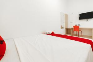 马卡萨RedDoorz @ Graha Cemerlang Maros的卧室配有红色椅子和白色床