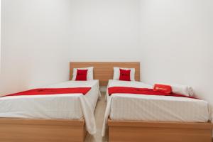 马卡萨RedDoorz @ Graha Cemerlang Maros的配有白色墙壁和红色枕头的客房内的两张床