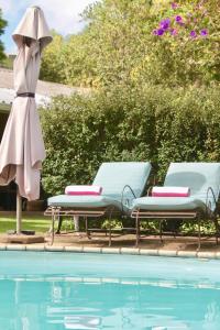 香槟谷Cathkin Cottage Bed & Breakfast的游泳池旁设有2把躺椅和遮阳伞