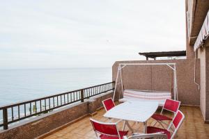 阿尔姆尼卡atico primera linea de playa的俯瞰大海的阳台配有桌椅