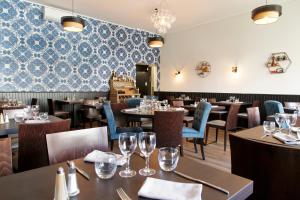 阿尔贝Logis Hotel & Restaurant de la Basilique的餐厅设有桌椅和蓝色瓷砖墙