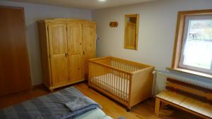 希尔兴巴赫Ferienhaus Broche的一间卧室配有一张婴儿床和木制橱柜。