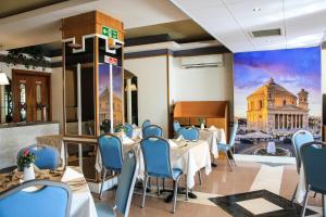 圣保罗湾城珊瑚酒店的一间设有桌椅的餐厅,并拥有一座建筑的壁画