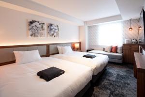 福冈HOTEL FORZA HAKATAEKI CHIKUSHIGUCHI Ⅱ的酒店客房,设有两张床和一张沙发