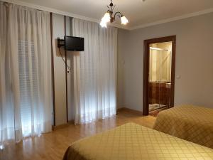 拉古纳德杜埃罗比利亚尔圣女旅馆的一间卧室设有两张床,墙上配有电视。