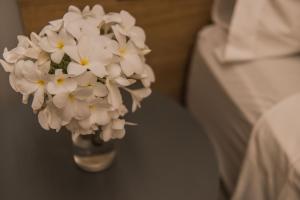 费尔南多 - 迪诺罗尼亚Pousada Corveta的睡床边的花瓶里满是白色的花朵