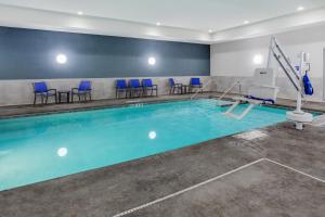 Rice LakeHoliday Inn Express & Suites - Rice Lake, an IHG Hotel的一个带蓝色椅子的游泳池