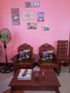 公主港Agimats Crib Palawan的一间设有两把椅子和一张桌子的房间,以及粉红色的墙壁
