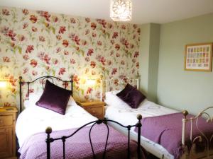 约克The Cloisters的卧室内的两张床,配有花卉壁纸