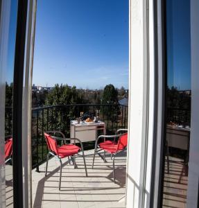 里摩日La Terrasse du Colombier的阳台设有红色椅子和一张桌子,享有美景。