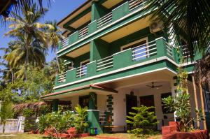 阿伯来Green Nest Hostel, Baga - Arpora的棕榈树的绿色白色建筑