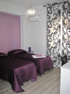巴勒莫阿玛瑞58号住宿加早餐旅馆的一间设有两张床和一张带紫色毯子的桌子的房间