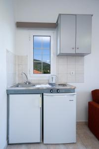 凯法利尼亚岛季米特里斯公寓旅馆的厨房配有白色橱柜、水槽和窗户。