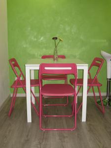 巴勒莫阿玛瑞58号住宿加早餐旅馆的一张桌子,上面有红色的椅子和一张白色的桌子,上面有花瓶