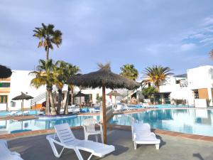 卡勒达德福斯特Puerta del Sol casa Lily Caleta de Fuste的度假村的游泳池,配有椅子和遮阳伞