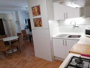 瓦伦西亚Apartamento cerca de la Ciudad de las Ciencias的厨房配有白色橱柜、水槽和桌子