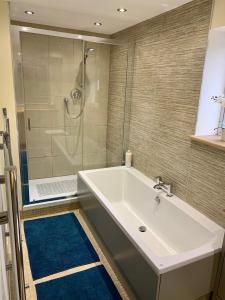 阿伯加文尼Deri-Down Guest House的一间带大型白色浴缸和淋浴的浴室