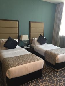 阿布扎比阿布扎比滨海路华美达酒店的两张位于酒店客房的床,拥有蓝色的墙壁